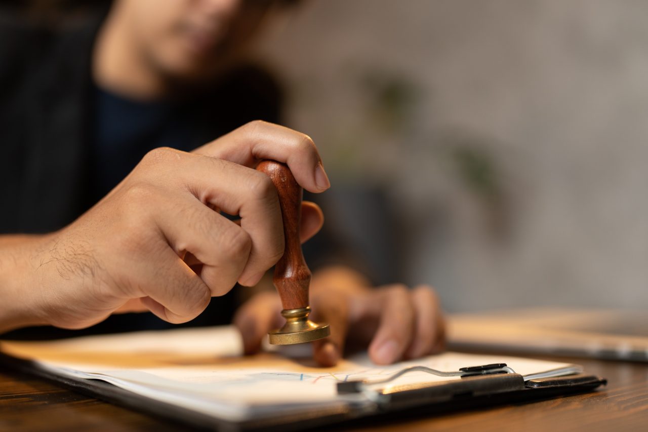 Hand stamping with approved stamp on certificate document public paper at desk notary or business.jpg